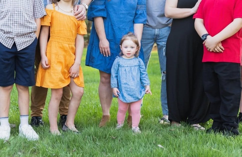 A row of children standing in the grass in bright coordinated outfits